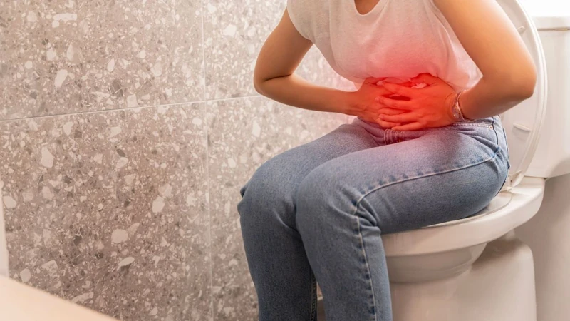 Woman with abdominal pain sitting on a toilet